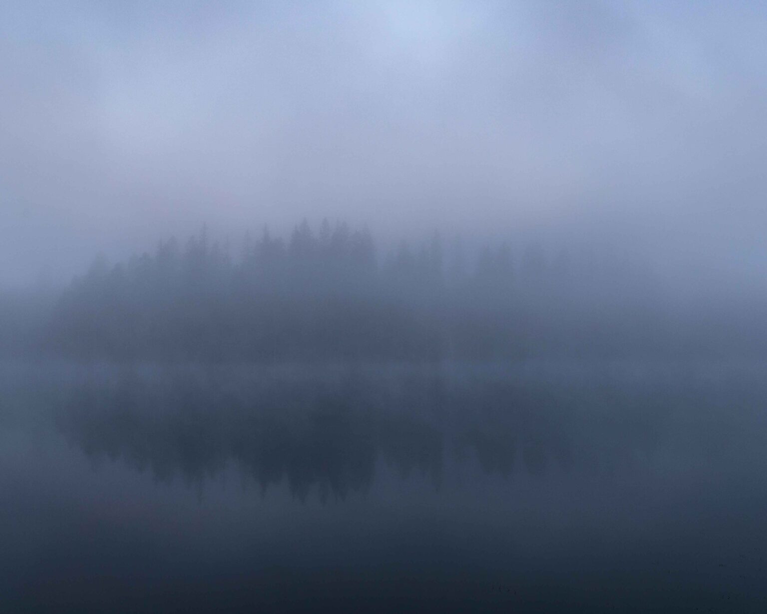 An islet mirrored in a misty lake